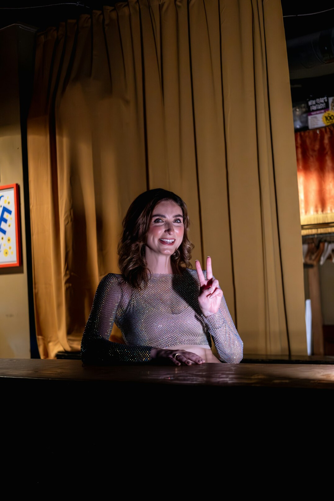 Smiling female television presenter in a modern news studio giving a thumbs up